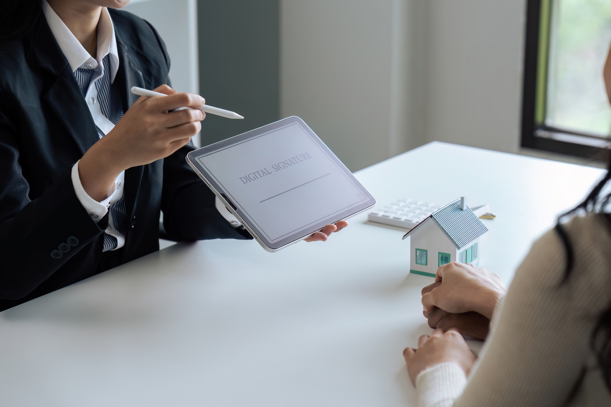 Real estate agent is explaining how to sign purchase contract using online signature. Sign on tablet